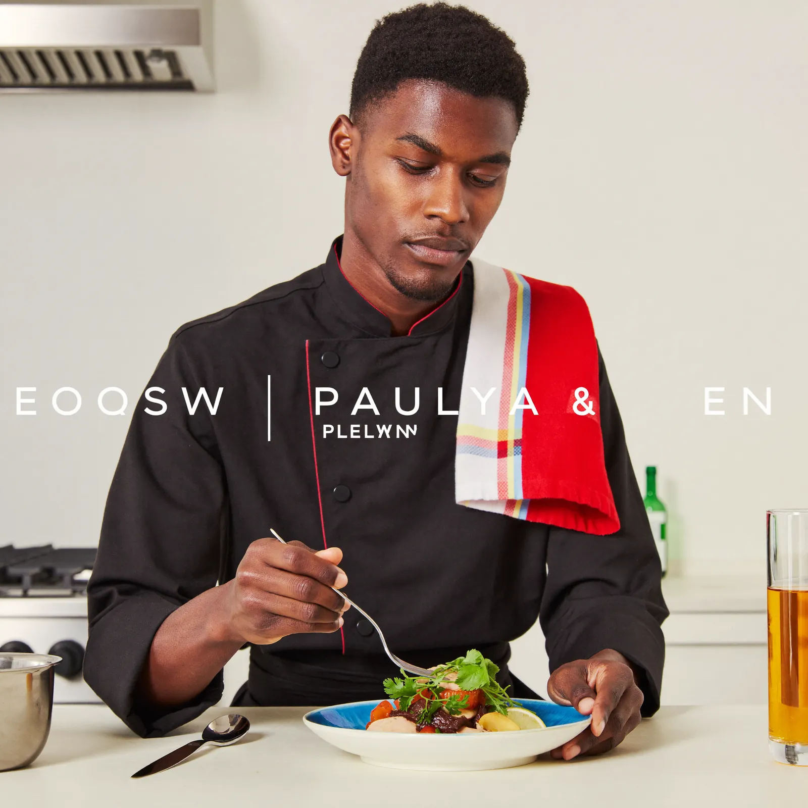 A chef plating a colorful dish in a bright, minimal studio kitchen.